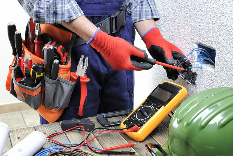 Young technician electrician measures with the multimeter the voltage in a residential electric installation.
